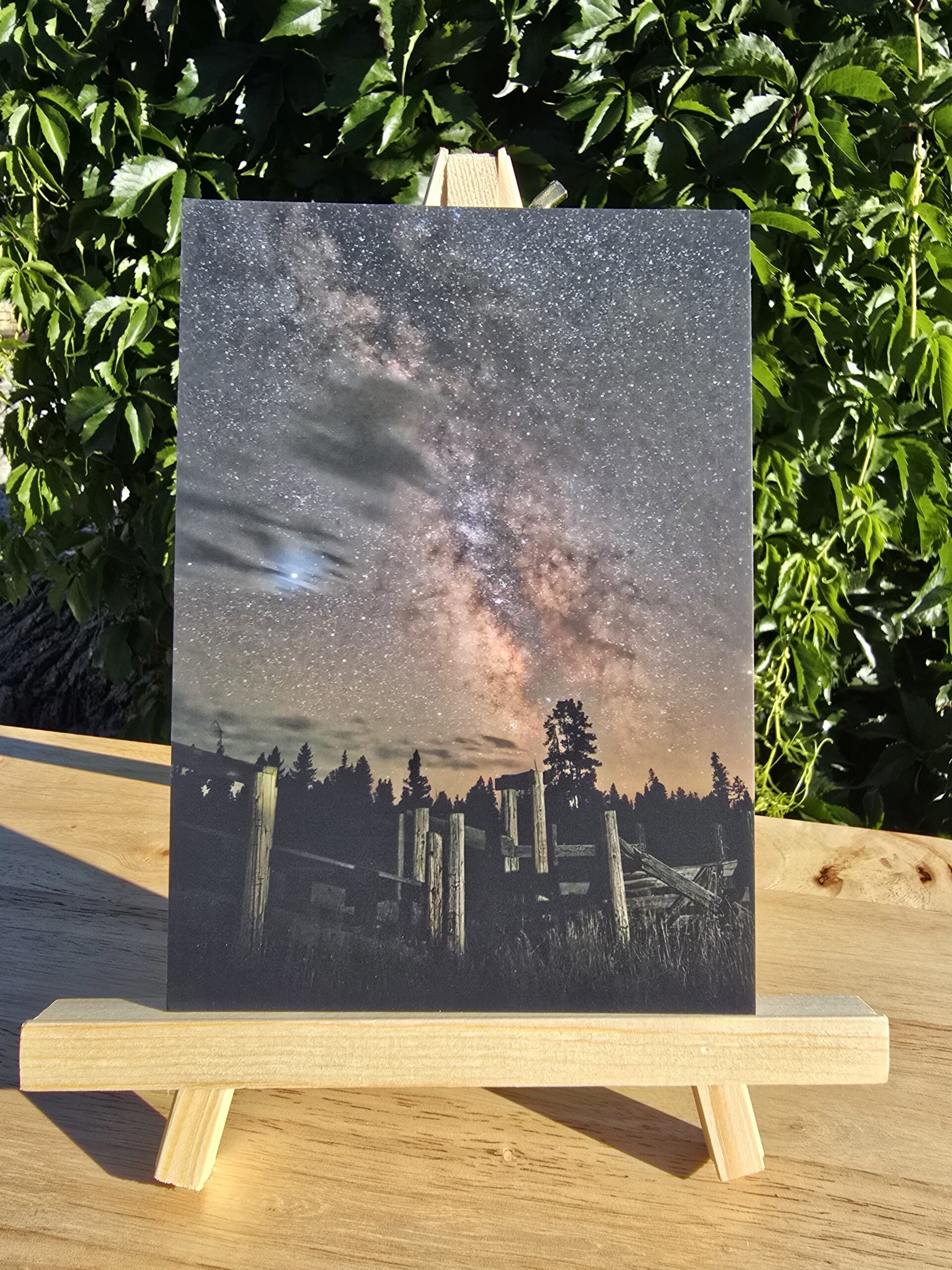 Postcard featuring Milky Way Over Corral displayed on a small wooden easel
